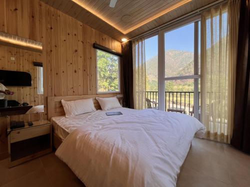 a bedroom with a large bed with a large window at Hotel Dev Darshan in Uttarkāshi