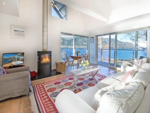 a living room with a white couch and a fireplace at Dipper Boathouse in Acharn