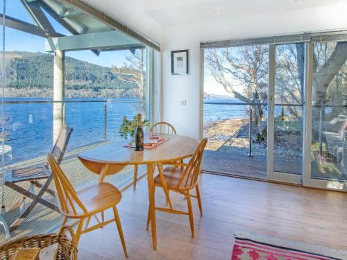 a dining room with a table and chairs and a large window at Dipper Boathouse in Acharn