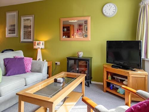 a living room with a couch and a tv at Dihangfa Wylau in Tywyn
