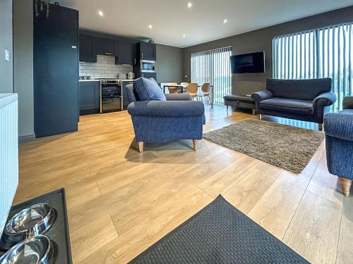 a living room with blue chairs and a kitchen at Bellstane Chalet - Ukc9440 in Glasgow