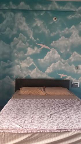 a bedroom with a bed with a cloudy wall at Sri Skandaa in Sringeri