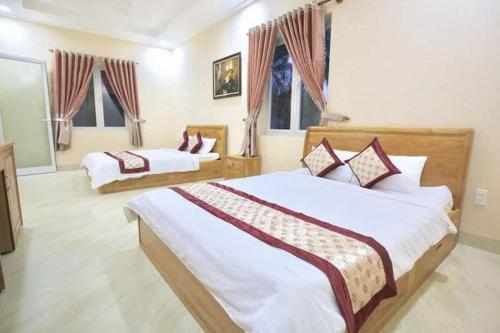 a bedroom with two beds and two windows at Sông Kinh Hotel - Hồ Tràm in Xóm Trương Quít
