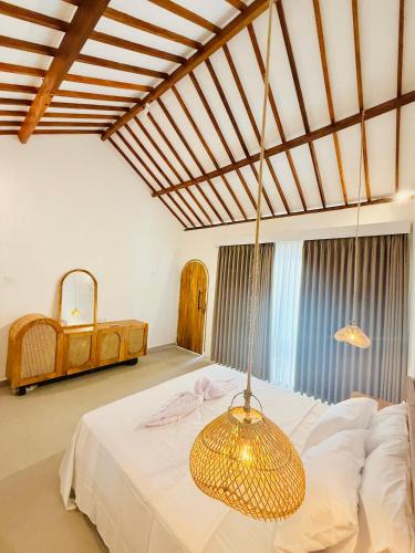 a bedroom with a large bed with a chandelier at ADIBA village in Gili Meno