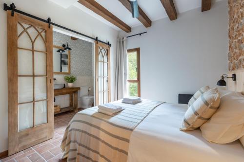 a bedroom with a large bed and a bathroom at Cal Moline Arrels - Refugio rural de diseño en el Berguedà in Graugés