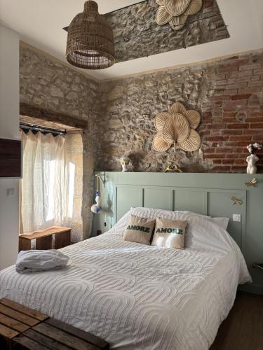 a bedroom with a large bed with a brick wall at Vénusté, Suite romantique in Périgueux