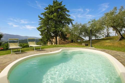 a swimming pool with two chairs and a tree at Fontesecca - Happy Rentals in Città della Pieve
