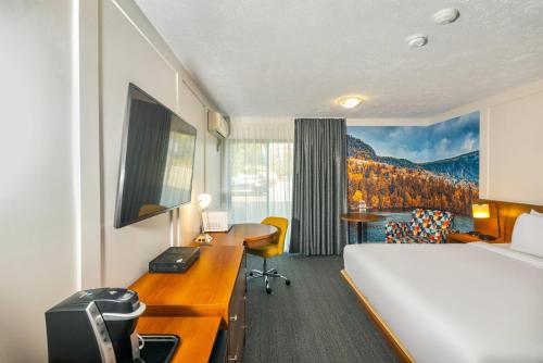 a hotel room with a bed and a desk at Clarion Pointe La Malbaie in La Malbaie