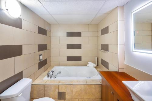 a bathroom with a tub and a toilet and a sink at Clarion Pointe La Malbaie in La Malbaie