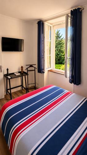 a bedroom with a colorful bed with a window at La Garçonnière appartement climatisé in Charolles