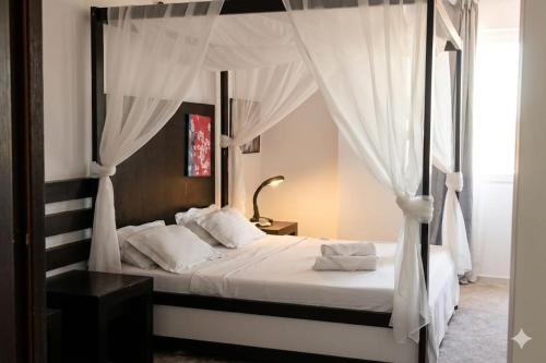a bedroom with a canopy bed with white curtains at Hotel Sydney in Craiova