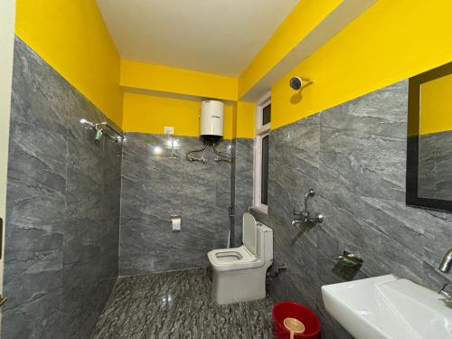 a bathroom with a toilet and a sink and yellow walls at Hotel Sonam Chen Residency Lachung in Lachung