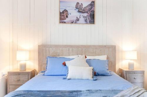 a bedroom with a bed with blue sheets and two lamps at 30A Urangan Beach Cottage (Front Property) in Urangan