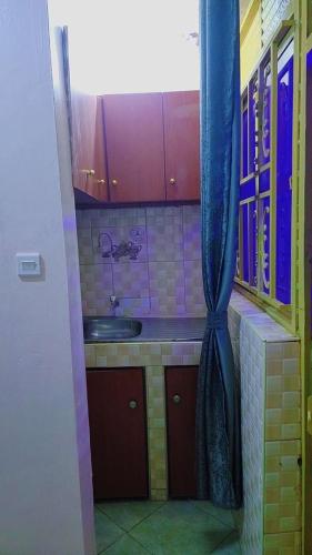 a small kitchen with a sink and a blue curtain at Zone hotel and guest house in Bugembe