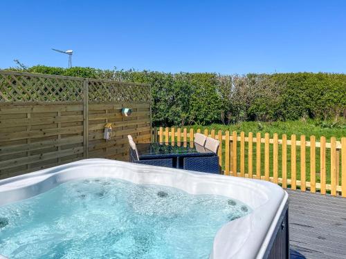 a hot tub on a deck with a table and a fence at Oak - Uk51863 in Reighton