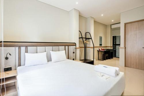 a bedroom with a white bed and a bathroom at Rucio Kostel Semarang in Jatingaleh