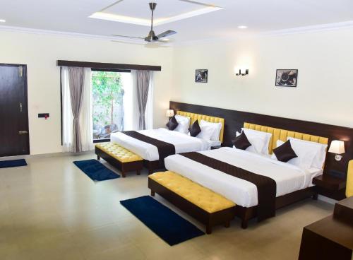 two beds in a hotel room with two chairs at The Pentouz Hillside Chikmagalur in Chikmagalūr