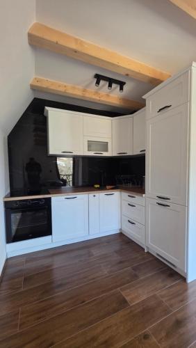 a kitchen with white cabinets and a wooden floor at Mini Garden PREMIUM in Mojkovac