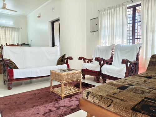 a living room with chairs and a bed and a table at Aromal Homestay in Kovalam