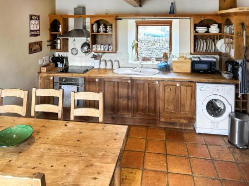 a kitchen with a sink and a washing machine at Ostlers End in Hartington