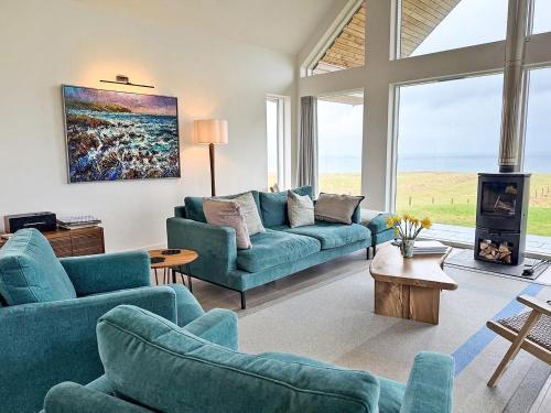 a living room with blue couches and a fireplace at Croft 105 in Melvich