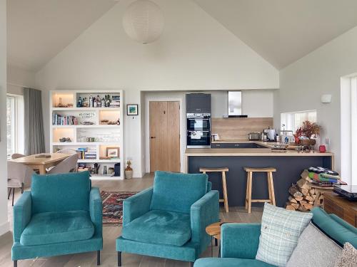 a living room with blue chairs and a kitchen at Croft 105 in Melvich