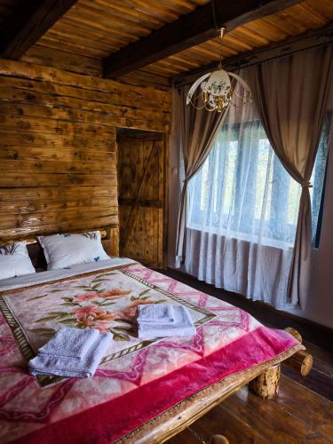 a bedroom with a bed with a wooden wall and a window at Căsuța de la munte in Bistriţa