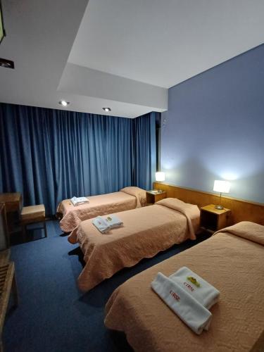 a hotel room with three beds with towels on them at Hotel cirse cr in Comodoro Rivadavia