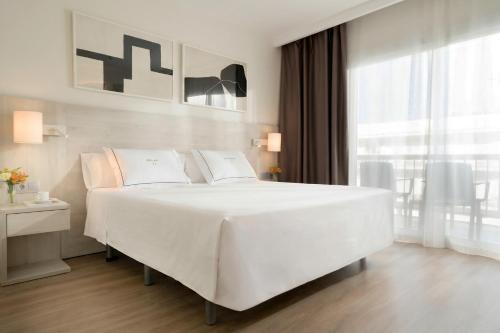 ein weißes Schlafzimmer mit einem großen weißen Bett und einem Fenster in der Unterkunft Hotel Helios Lloret in Lloret de Mar