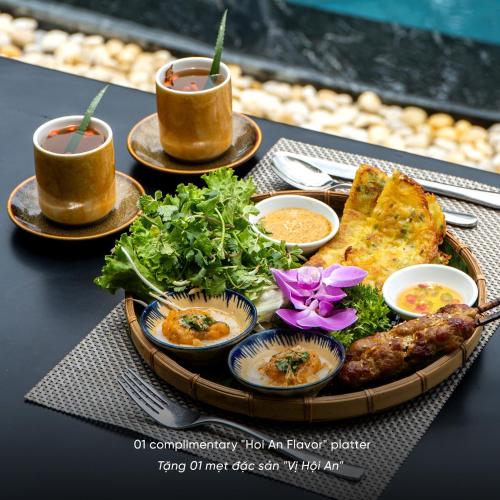 a table with a plate of food and two cups of tea at Lantern Boutique Hoi An in Hoi An