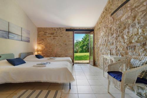 a bedroom with two beds and a stone wall at Gite Le Mas in Corgnac-sur-lʼIsle