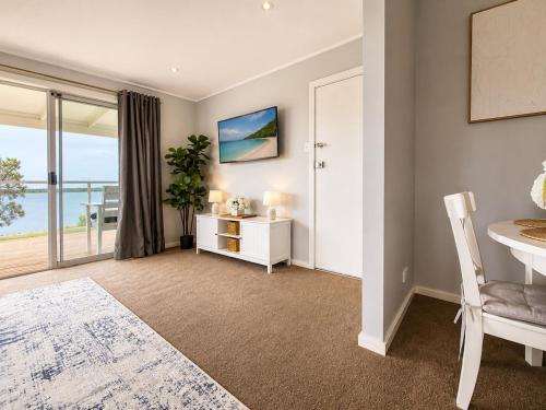 a living room with a table and a view of the ocean at Anita Cottage waterfront in Lake Munmorah
