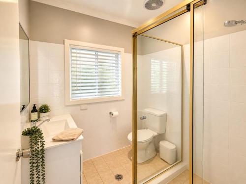 a bathroom with a shower and a toilet and a sink at Anita Cottage waterfront in Lake Munmorah