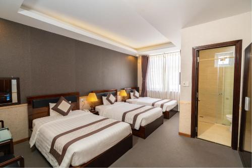 a hotel room with two beds and a shower at Navy Hotel Da Lat in Da Thien