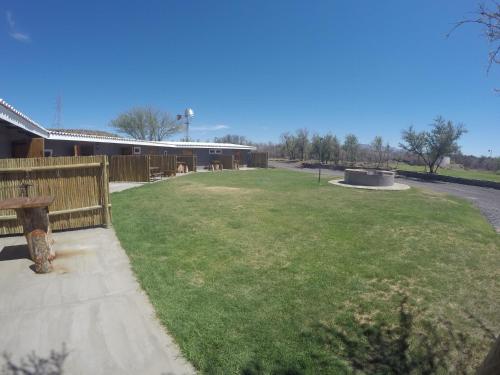 a large field of grass with a building in the background at Teri-Lemveli Lodge in Beaufort West