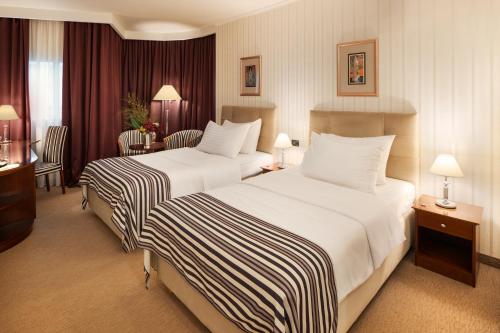 a hotel room with two beds and a desk at Hotel Dubrovnik in Zagreb