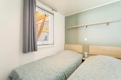 a bedroom with two beds and a window at Bungalow in Canet-en-Roussillon