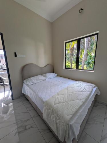 a bedroom with a white bed with a window at Shareen Homestay Morib in Banting