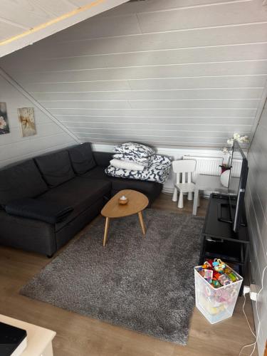 a living room with a black couch and a table at Bjarmaland in Vestmannaeyjar