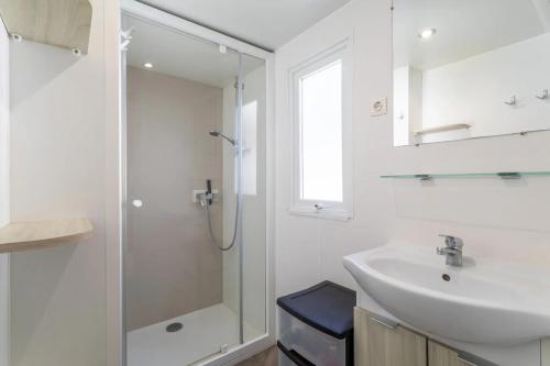 a white bathroom with a sink and a shower at Bungalow in Canet-en-Roussillon