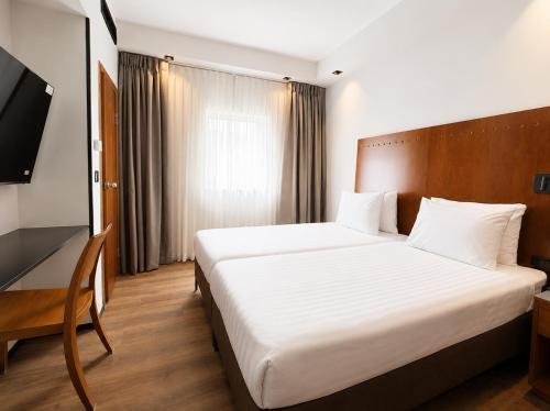 ein Schlafzimmer mit einem großen weißen Bett und einem Fernseher in der Unterkunft SeaNet Hotel By AFI Hotels in Tel Aviv