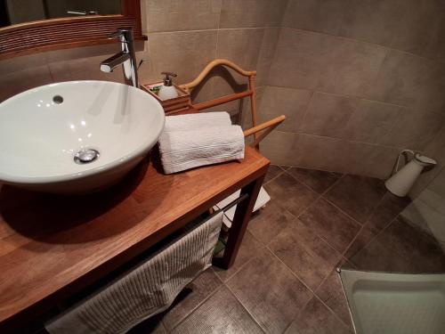 a bathroom with a white sink on a wooden counter at Les Logis de Léa in Saint-Beauzély