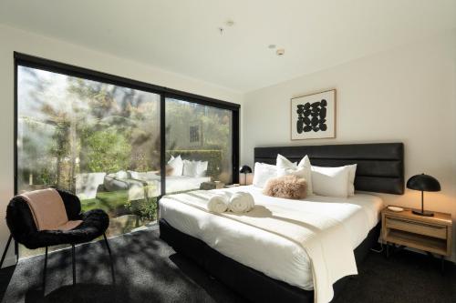 a bedroom with a large bed and a large window at Hygge Garden Apartment with Private Sauna in Queenstown