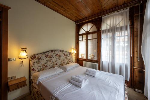 una camera da letto con un letto con lenzuola bianche e una finestra di Hotel Posta R.T.A. a Madonna di Campiglio
