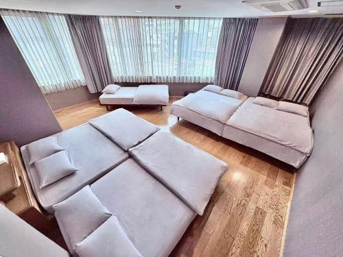 ein großes Wohnzimmer mit weißen Möbeln und Fenstern in der Unterkunft Maria Hotel 宇都宮 in Utsunomiya