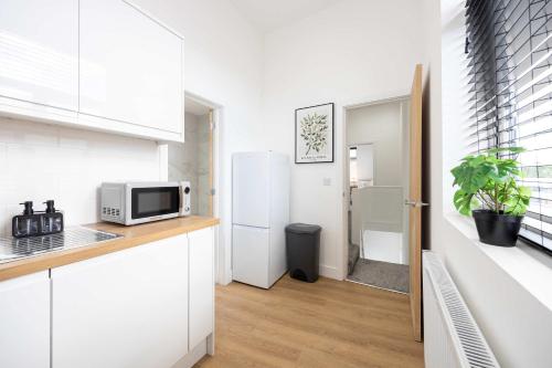 a kitchen with white cabinets and a white refrigerator at The Loft Apartment in Elland