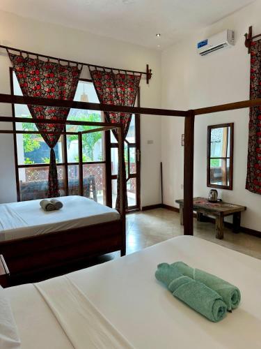 a bedroom with two beds and a large window at vayana nungwi in Nungwi