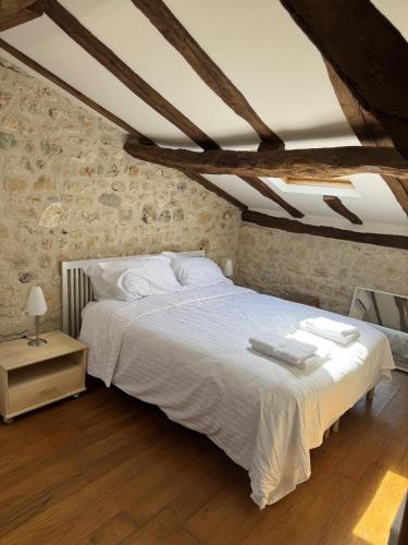 a bedroom with a white bed in a brick wall at Fontaine de Champagne in Champagne-et-Fontaine