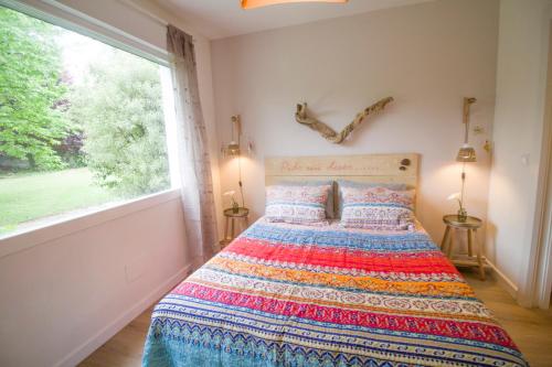 a bedroom with a bed and a large window at La Casa del Petirrojo de Ribamontan al Mar con Surf y Tranquilidad in Castanedo