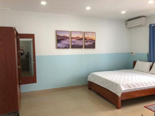 a bedroom with a bed and three paintings on the wall at Homestay 150 in Ho Chi Minh City